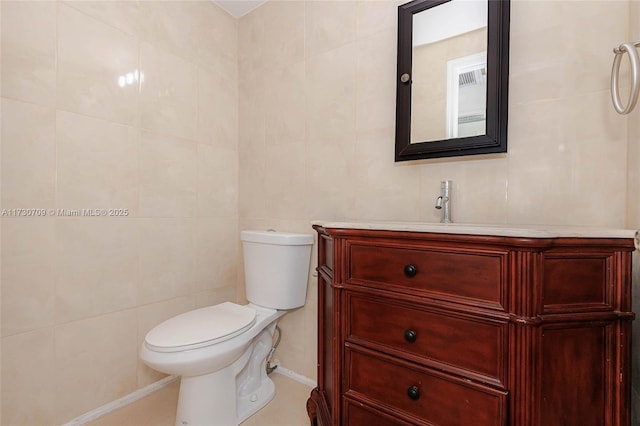 bathroom with vanity, toilet, and tile walls