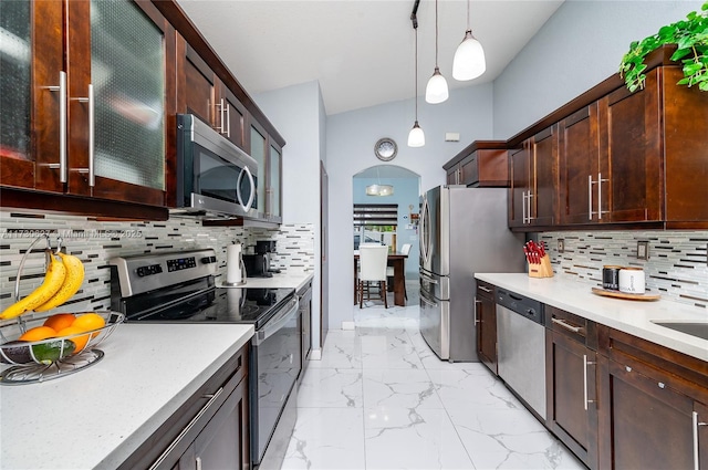 kitchen with decorative light fixtures, backsplash, light stone countertops, and stainless steel appliances