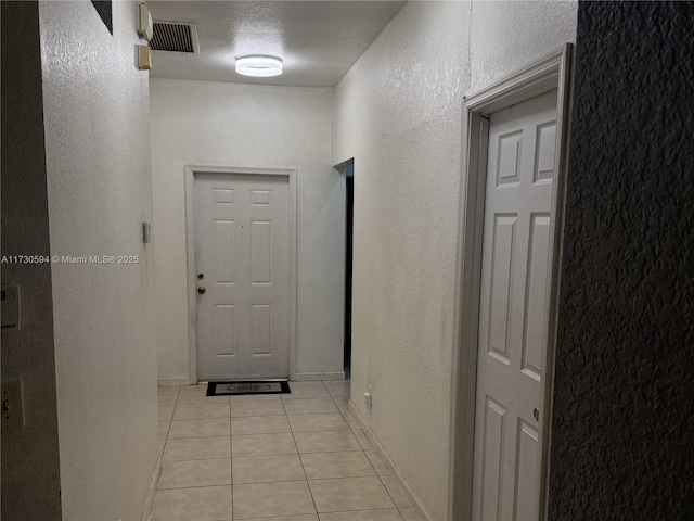 hallway featuring light tile patterned floors and a textured ceiling