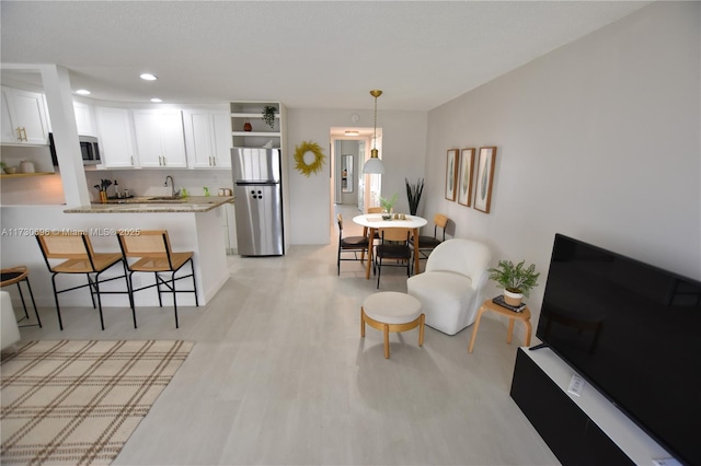 kitchen featuring appliances with stainless steel finishes, decorative light fixtures, white cabinetry, a breakfast bar area, and kitchen peninsula