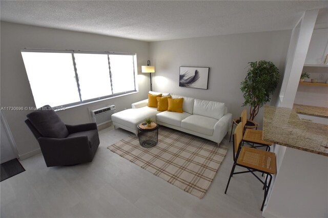 living room with a wall unit AC and a textured ceiling