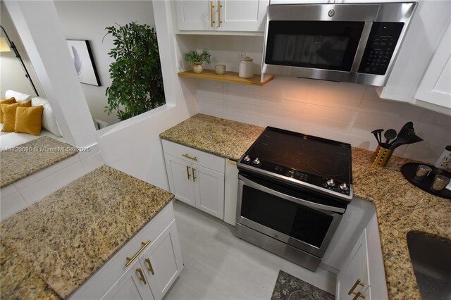 kitchen with light stone counters, backsplash, white cabinets, and appliances with stainless steel finishes