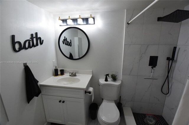 bathroom featuring a tile shower, vanity, and toilet