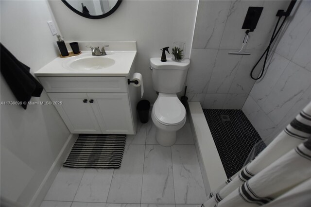 bathroom with vanity, tiled shower, and toilet