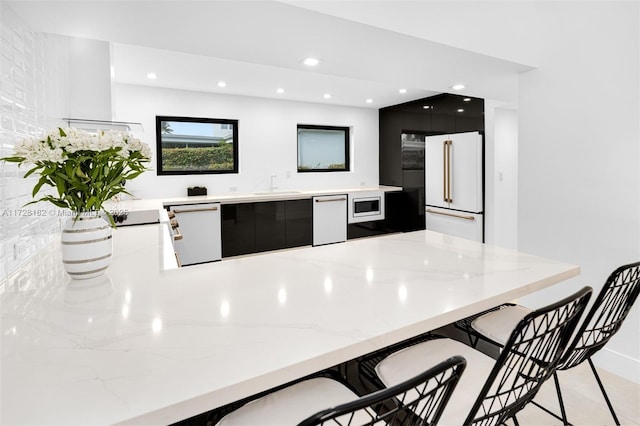 kitchen with a kitchen breakfast bar, white appliances, kitchen peninsula, and sink