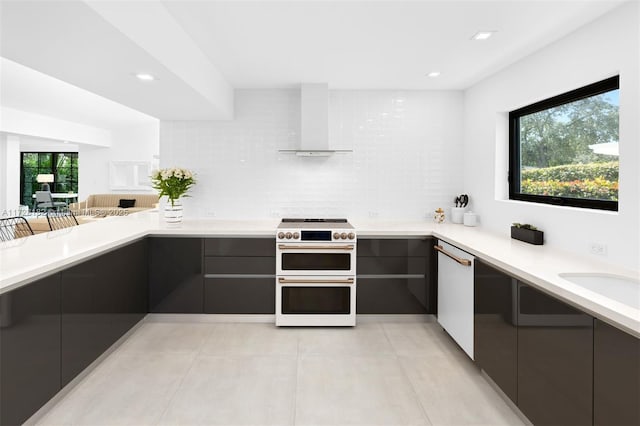 kitchen featuring sink, white appliances, wall chimney exhaust hood, and a healthy amount of sunlight