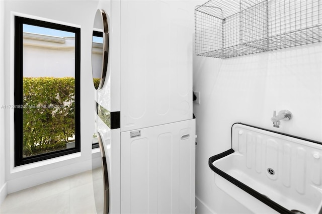 laundry room with sink, stacked washer and clothes dryer, and light tile patterned flooring