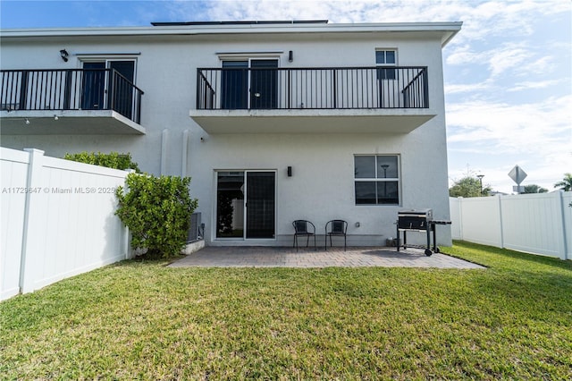 rear view of property featuring a balcony, a lawn, and a patio area