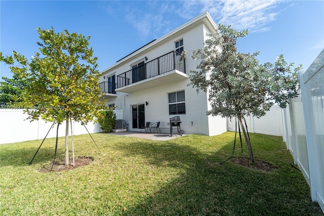 rear view of property featuring a balcony, a patio area, cooling unit, and a yard