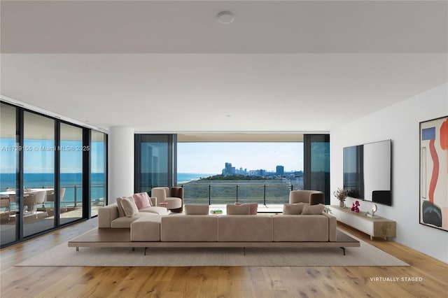 living room featuring a wealth of natural light, light hardwood / wood-style flooring, a water view, and expansive windows