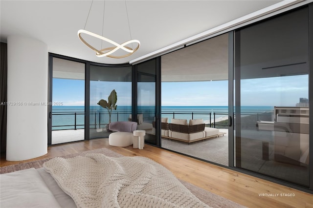 bedroom featuring a water view, expansive windows, access to exterior, and wood-type flooring