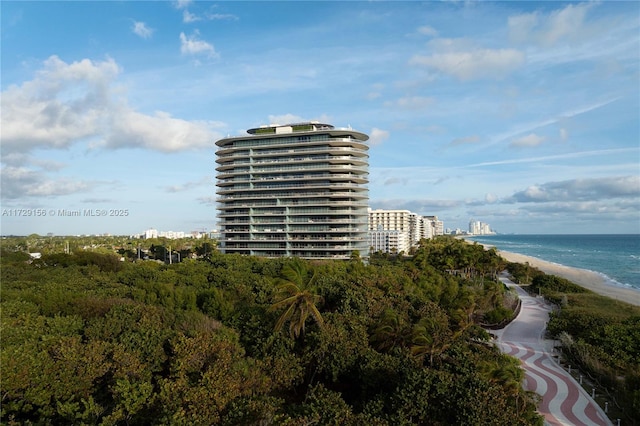 view of building exterior featuring a water view and a beach view