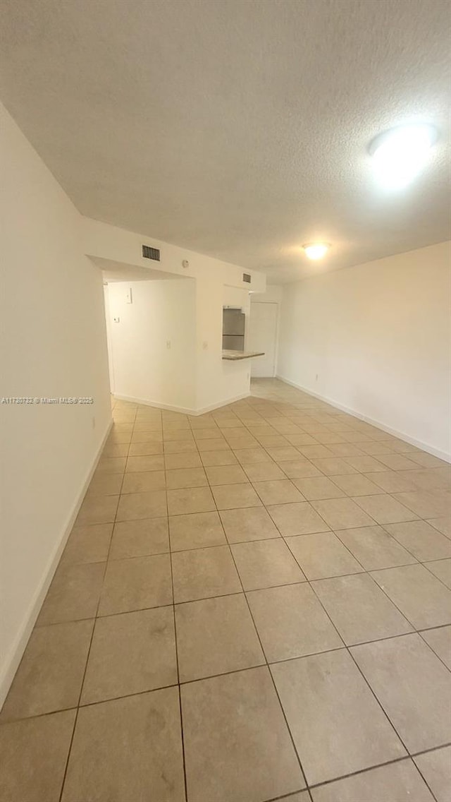 unfurnished room with light tile patterned floors and a textured ceiling