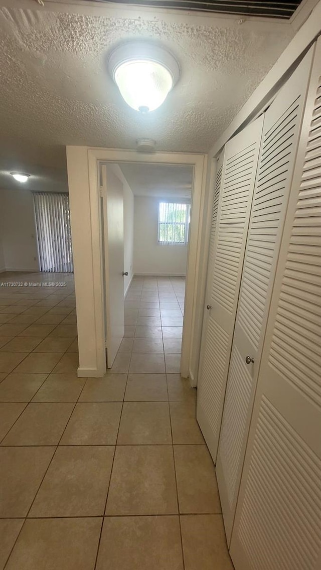 corridor with light tile patterned floors and a textured ceiling