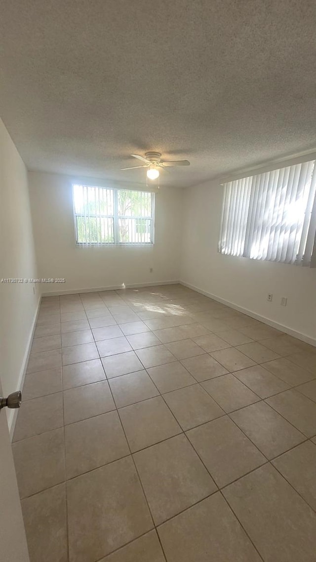 tiled spare room with a textured ceiling and ceiling fan