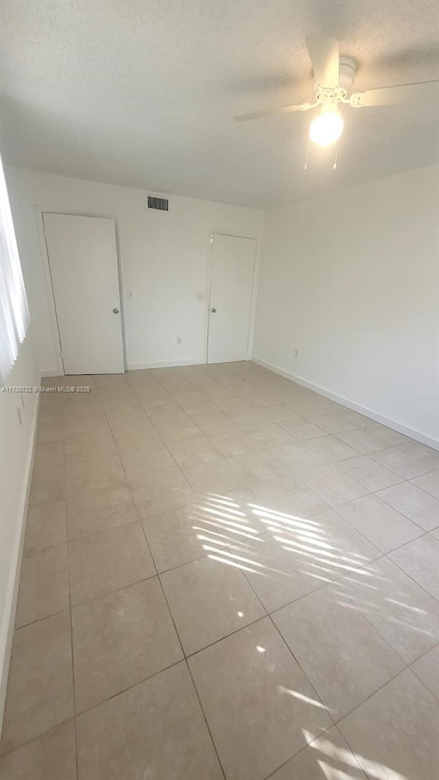 unfurnished room featuring a textured ceiling, light tile patterned floors, and ceiling fan