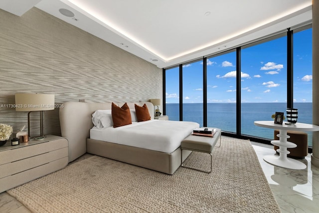 bedroom featuring access to outside, expansive windows, and a water view