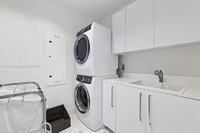 laundry room featuring cabinets, stacked washer / dryer, and sink