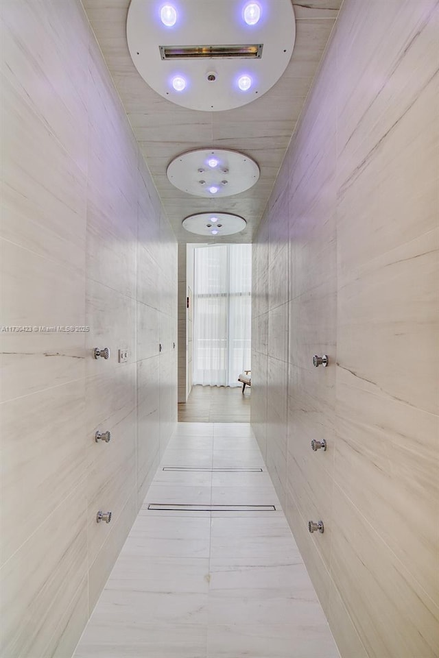 hall featuring tile walls and light tile patterned floors