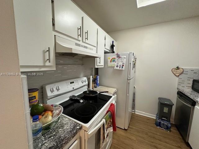 kitchen with white cabinetry, dark wood-type flooring, white appliances, and backsplash