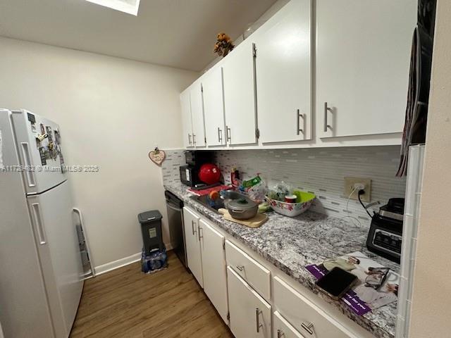 kitchen with white refrigerator, white cabinetry, refrigerator, and tasteful backsplash