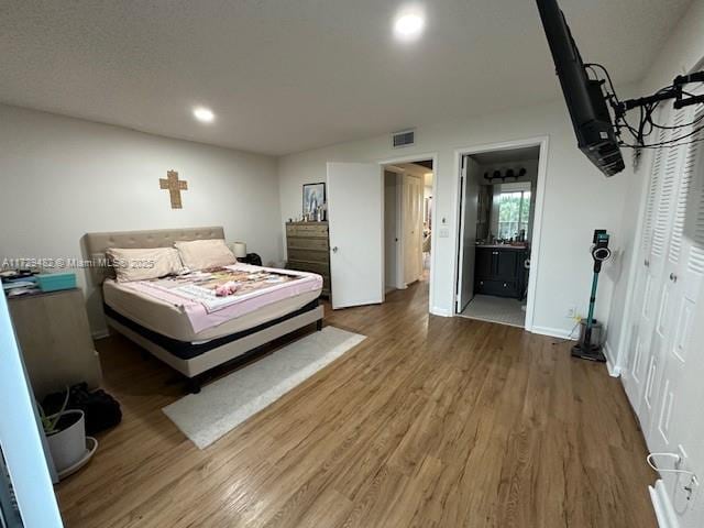 bedroom featuring wood-type flooring and ensuite bath