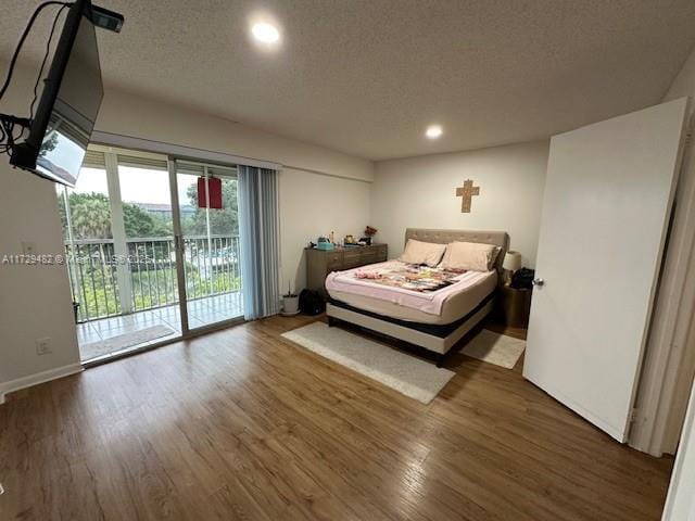 bedroom with dark wood-type flooring, a textured ceiling, and access to outside