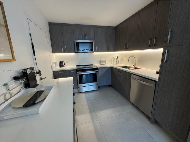 kitchen with appliances with stainless steel finishes, sink, and light tile patterned floors