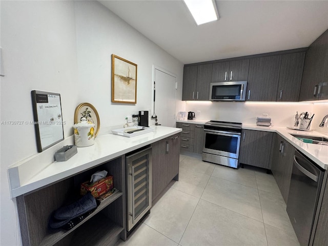 kitchen featuring appliances with stainless steel finishes, beverage cooler, sink, and light tile patterned floors