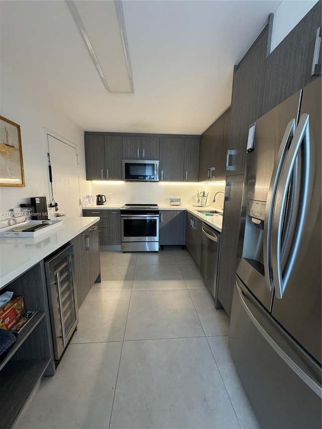 kitchen featuring light tile patterned floors, beverage cooler, and appliances with stainless steel finishes