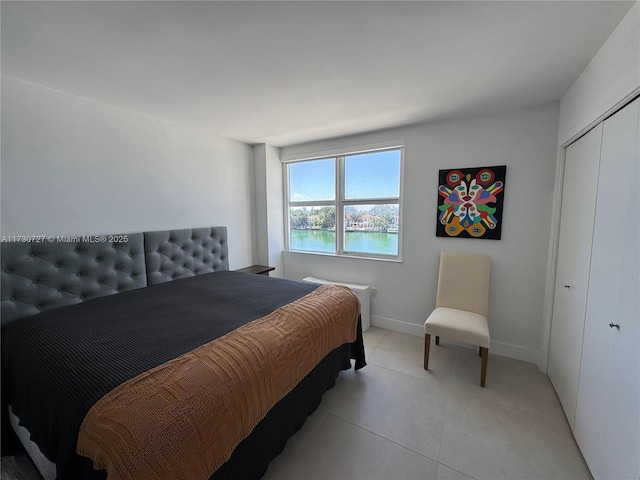 bedroom with a water view, light tile patterned floors, and a closet