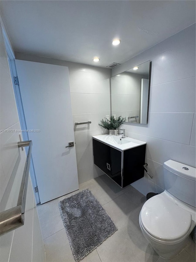 bathroom with tile walls, vanity, tile patterned floors, and toilet