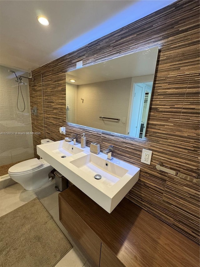 bathroom featuring tile walls, tile patterned flooring, tiled shower, vanity, and toilet