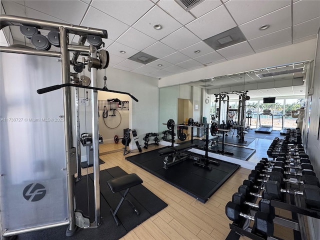 workout area with a paneled ceiling and wood-type flooring