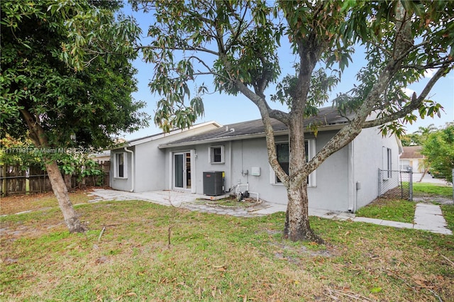 back of property featuring cooling unit and a lawn