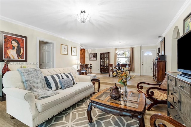 living room featuring a chandelier, light hardwood / wood-style flooring, and ornamental molding