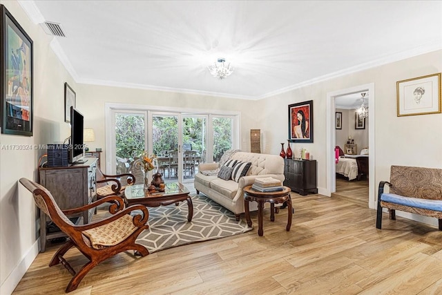 living room featuring crown molding, a chandelier, and light hardwood / wood-style flooring