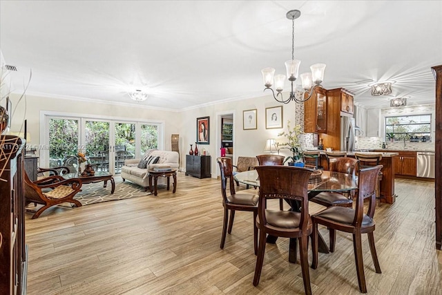 dining area featuring crown molding, a chandelier, and light hardwood / wood-style flooring