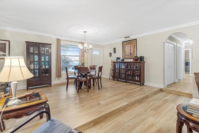 dining room with light hardwood / wood-style floors, ornamental molding, and an inviting chandelier