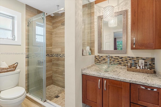 bathroom featuring decorative backsplash, toilet, walk in shower, and vanity