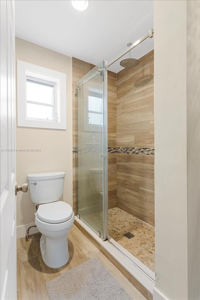 bathroom with wood-type flooring, toilet, and an enclosed shower