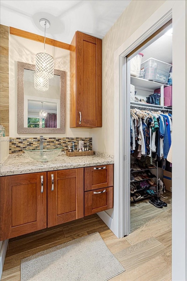 bathroom with hardwood / wood-style floors, backsplash, a notable chandelier, and vanity