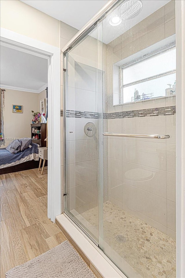 bathroom featuring hardwood / wood-style flooring, a shower with door, and ornamental molding