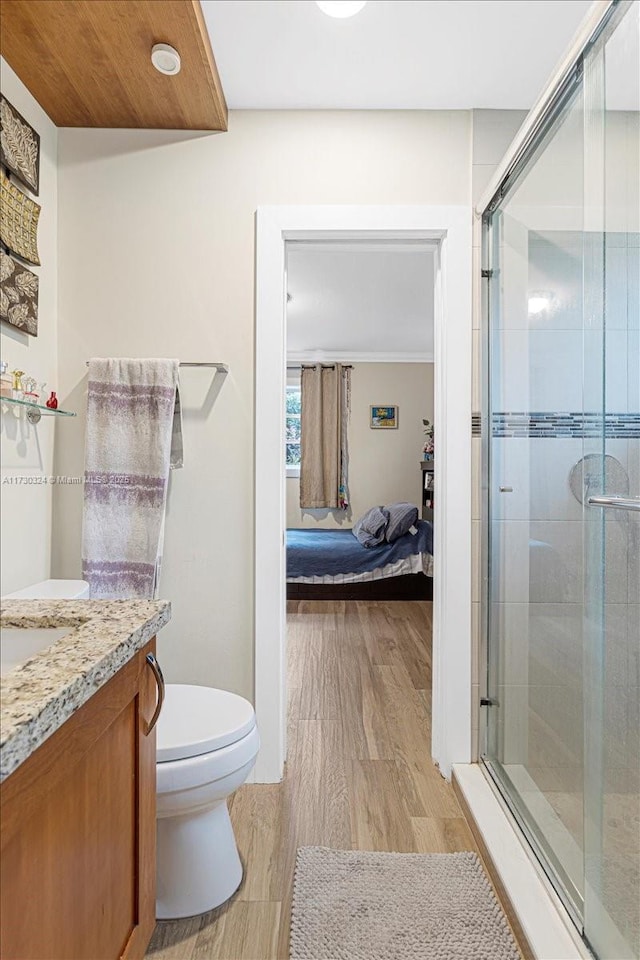 bathroom featuring vanity, hardwood / wood-style flooring, walk in shower, and toilet