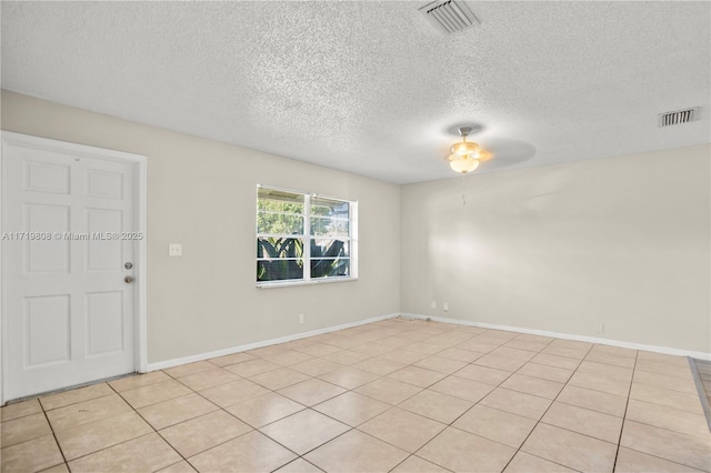 spare room featuring ceiling fan, light tile patterned floors, and a textured ceiling