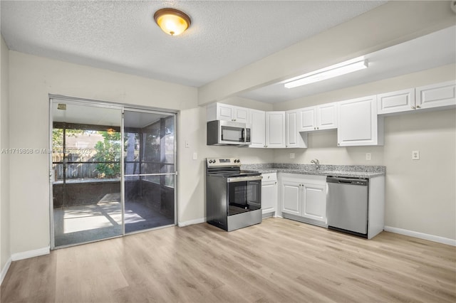 kitchen featuring a textured ceiling, white cabinetry, light hardwood / wood-style flooring, and stainless steel appliances