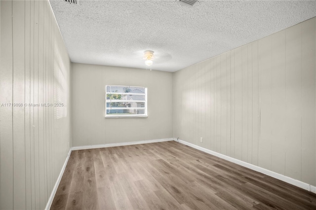 empty room featuring wood walls, hardwood / wood-style flooring, and ceiling fan