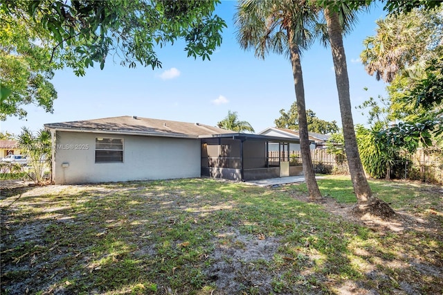 back of property with a sunroom and a lawn