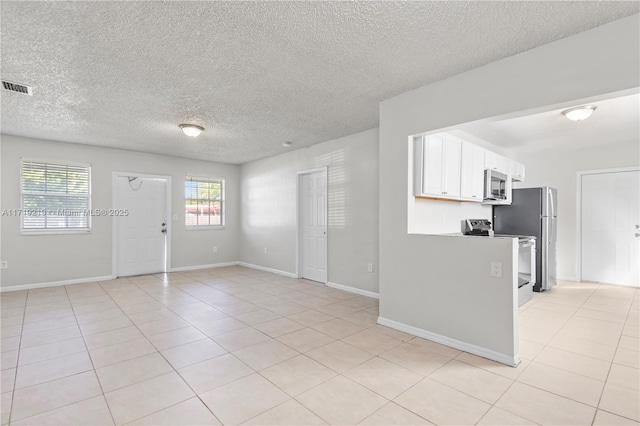 interior space featuring a textured ceiling, light tile patterned floors, and a healthy amount of sunlight