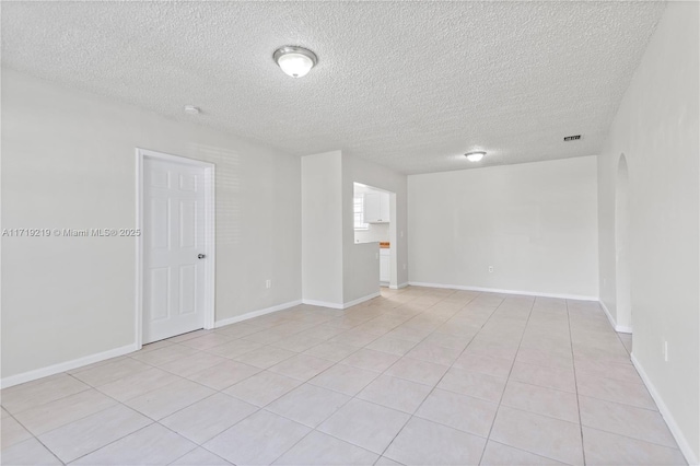 empty room featuring a textured ceiling and light tile patterned floors